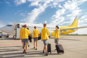 Tripulação de comissários de bordo caminhando em direção à aeronave, representando os requisitos para comissário de bordo